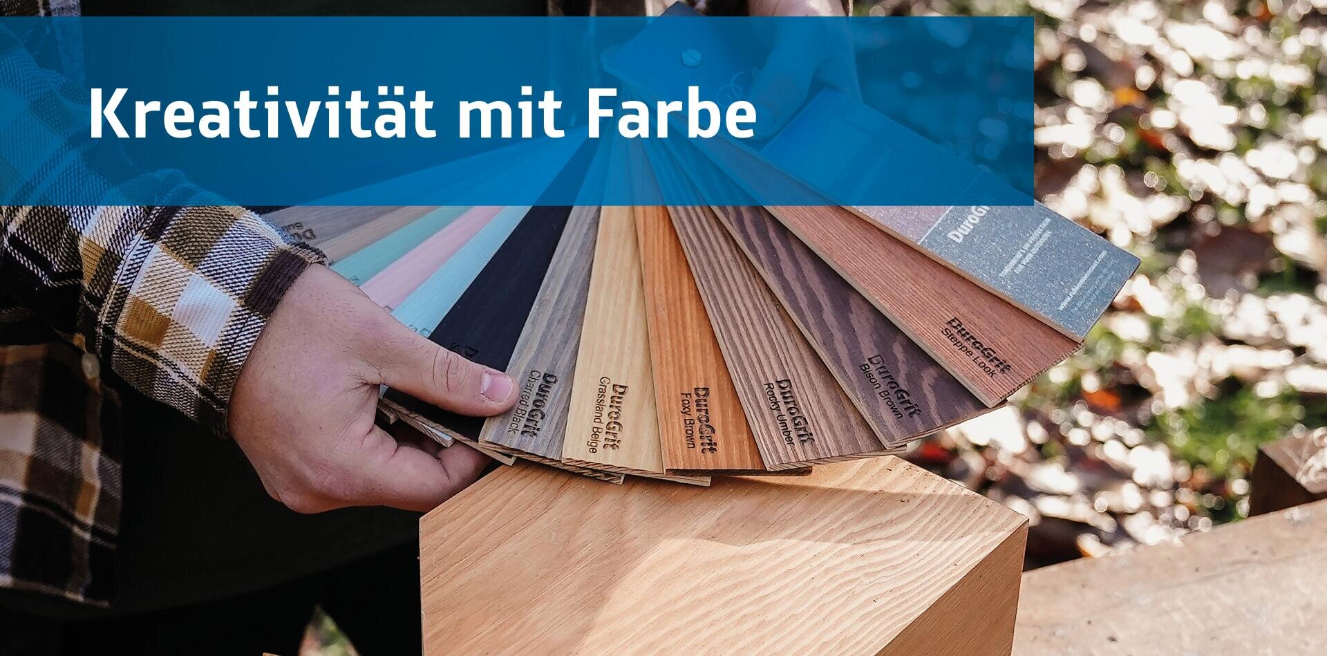 Eine Person hält einen Fächer mit hölzernen Farbmustern im Freien über einem Holzblock. Der Text Kreativität mit Farbe erscheint in einem blauen Banner am oberen Rand.