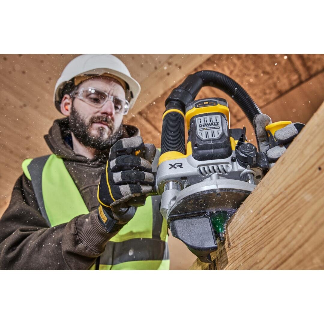 Ein Bauarbeiter in Schutzausrüstung fräst mit einem Elektrowerkzeug von DeWalt XR die Kante eines Holzbretts, wobei Holzspäne durch die Luft fliegen.