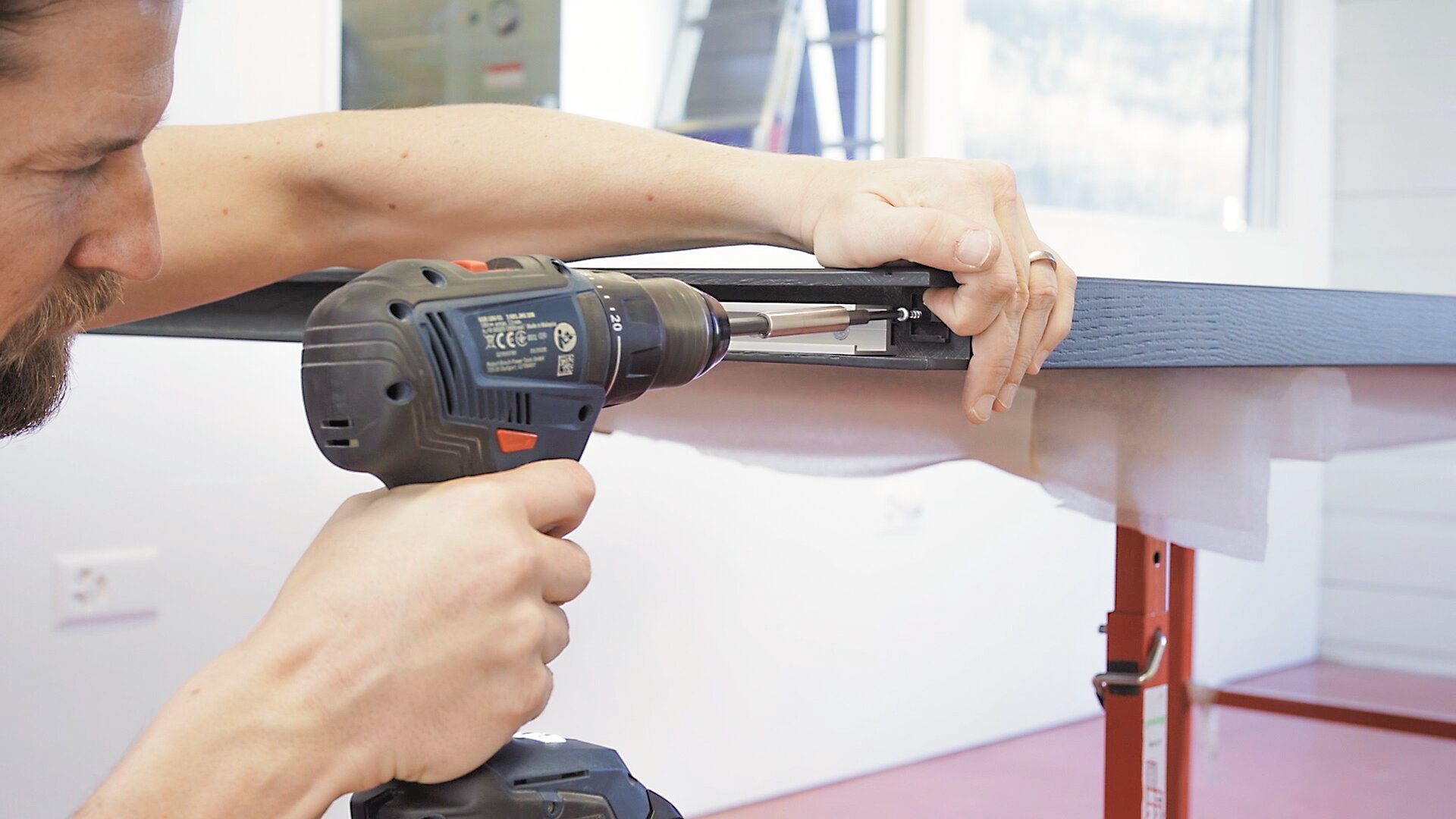 Une personne utilisant une perceuse pour percer une pièce de bois.