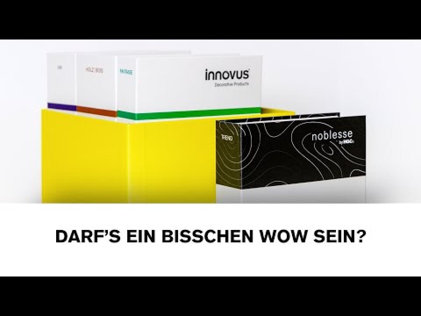 Mehrere bunte Produktmusterkarten stehen in einer gelben Schachtel. Die vordere Karte ist schwarz-weiß und trägt die Aufschrift noblesse und HIMACS. Der Text darunter lautet: DARF'S EIN BISSCHEN WOW SEIN?.