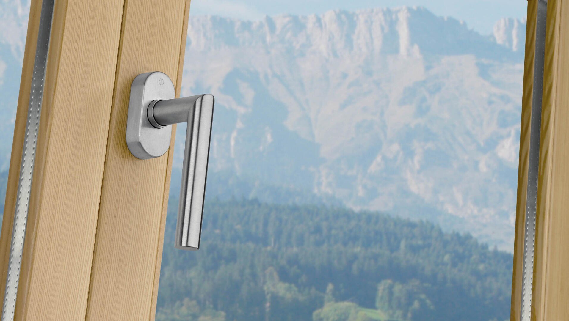Nahaufnahme eines Metall-Fenstergriffs an einem Fenster mit Holzrahmen, mit einer malerischen Aussicht auf Berge und Wälder im Hintergrund.
