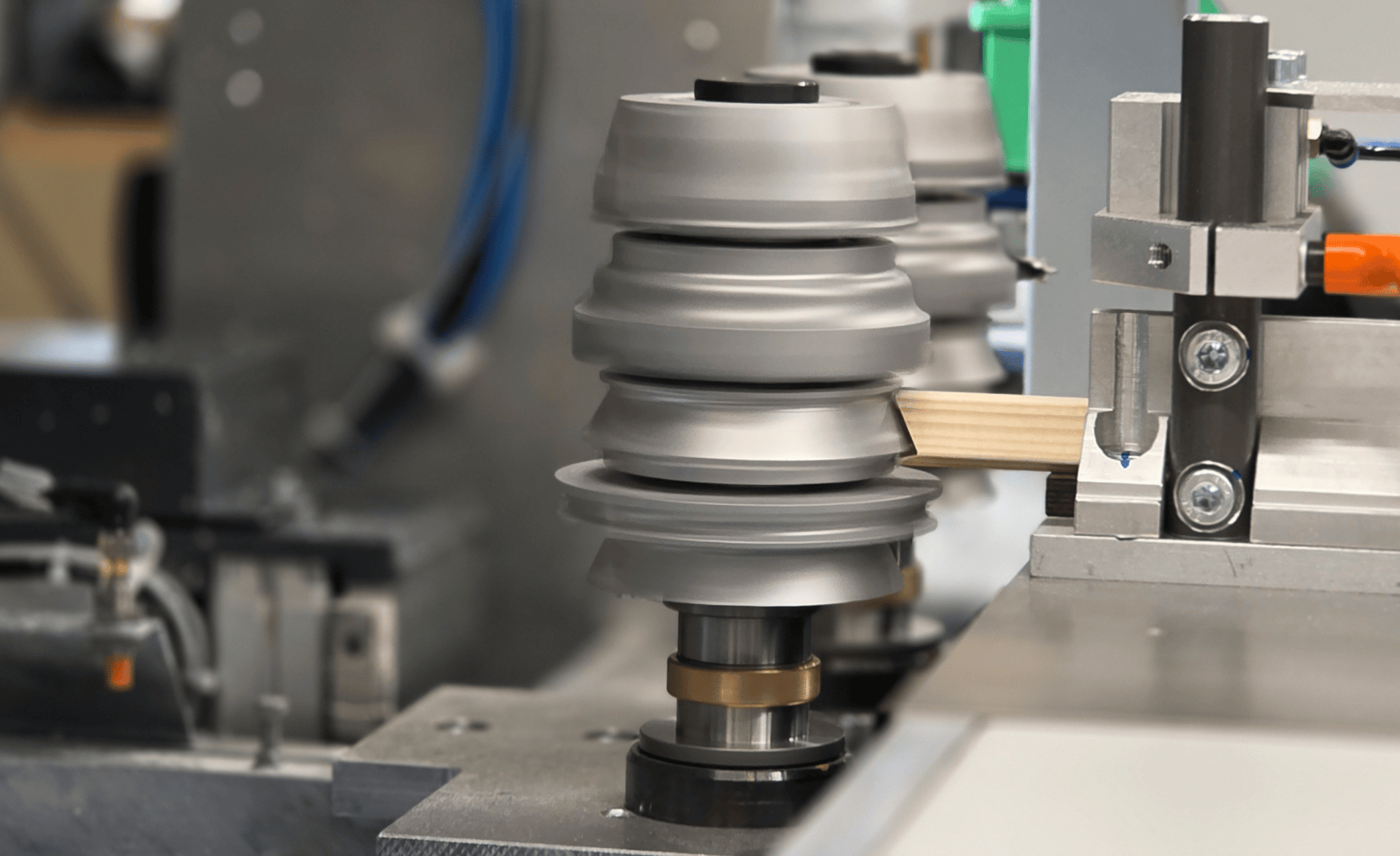 Gros plan d'une machine à bois industrielle en fonctionnement, avec des pièces de bois façonnées et lissées par des rouleaux métalliques en rotation et des outils de coupe.