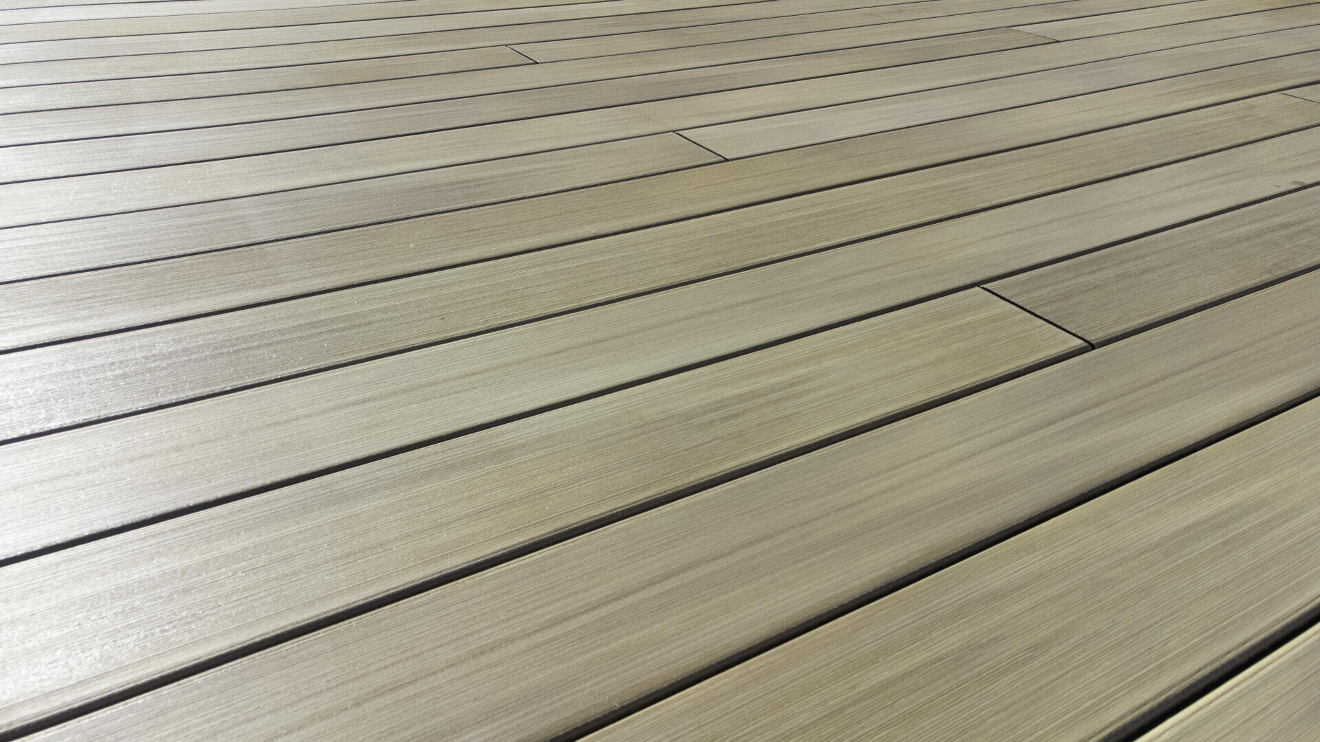 Nahaufnahme einer Holzterrasse mit gleichmäßig verteilten, hellbraunen Dielen, die in einem parallelen Muster angeordnet sind und eine glatte Textur und subtile Holzmaserung aufweisen.