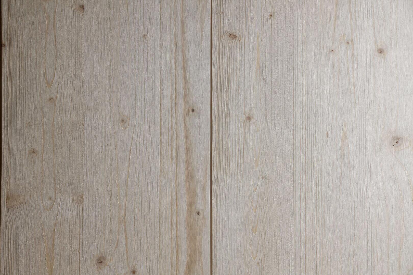 Nahaufnahme von zwei hellen Holzplatten nebeneinander, die die natürliche Maserung, die Äste und die subtilen Farbunterschiede des Holzes zeigen.