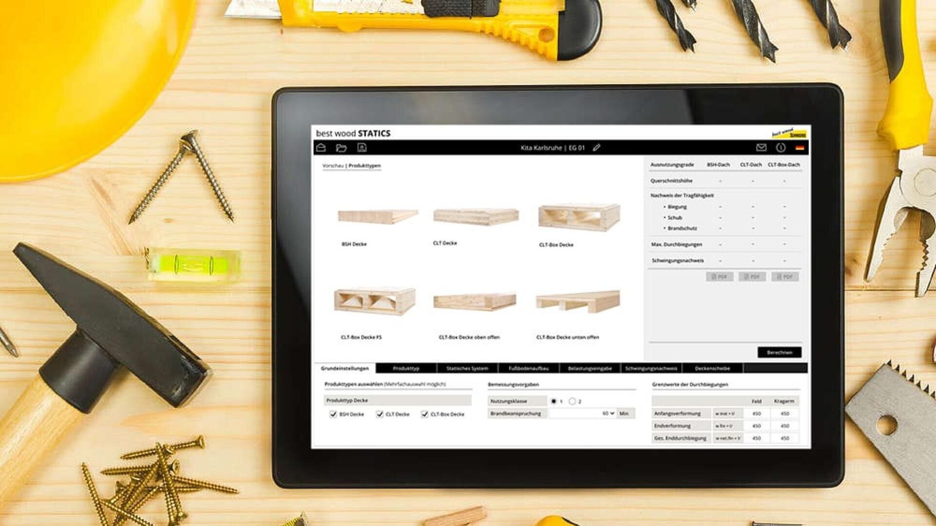 Auf einem Holztisch steht ein Tablet mit einem Produktkatalog für die Holzverarbeitung, umgeben von Werkzeugen wie Hammer, Maßband, Wasserwaage, Zange, Schutzbrille, Bleistift und einem gelben Schutzhelm.