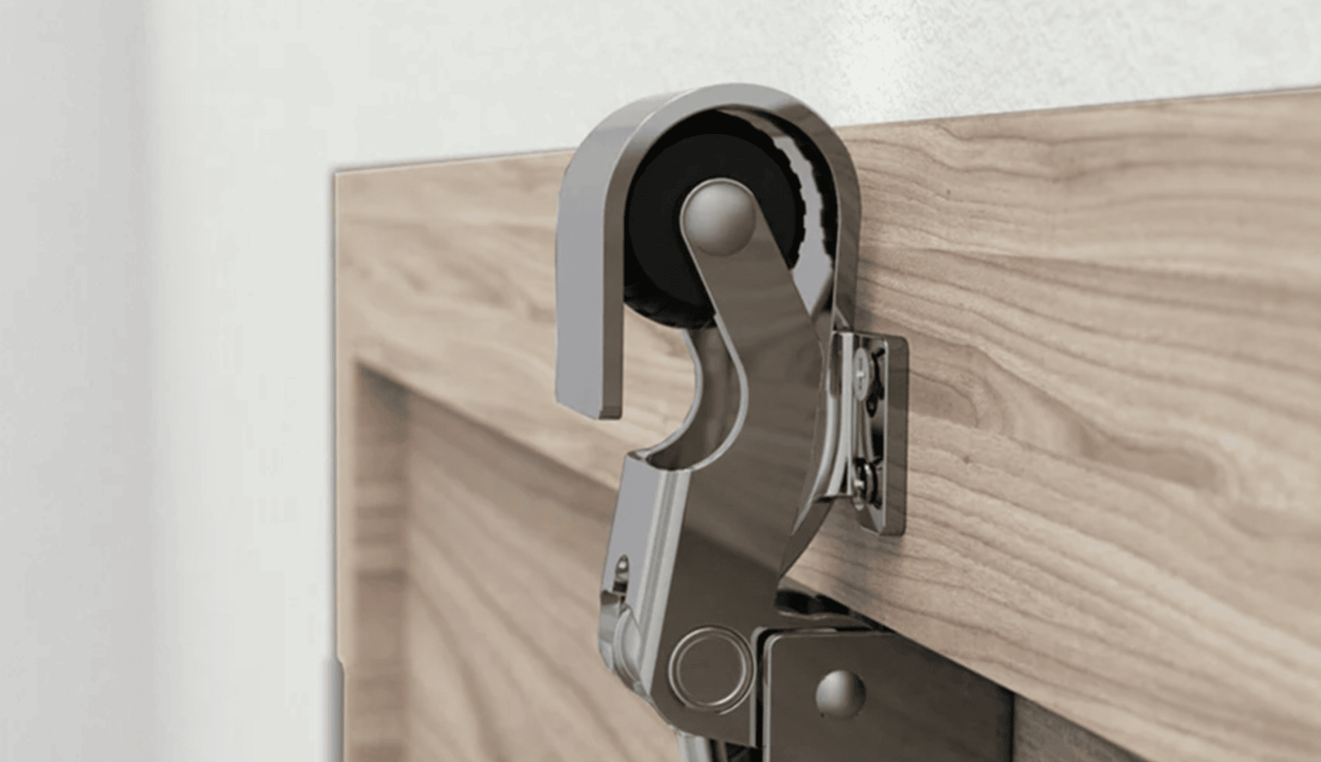 Nahaufnahme eines Türscharniers aus Metall mit einem schwarzen Kieselstein, der an der Oberkante einer Holztür befestigt ist, die neben einer weißen Wand montiert ist.