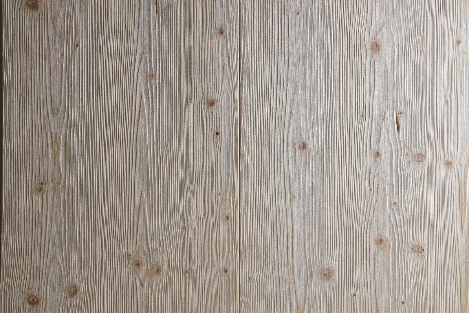 Helle Holzoberfläche mit sichtbaren natürlichen Maserungen und mehreren kleinen Ästen. Die Textur und die vertikalen Linien verleihen ihm ein rustikales, organisches Aussehen.