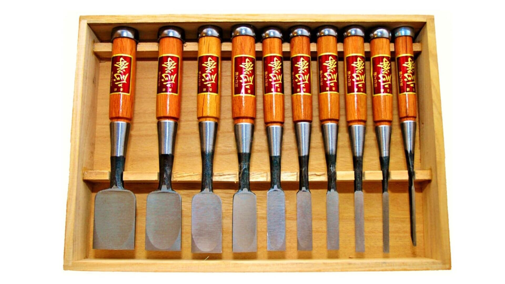 Holzkiste mit einem Satz von zehn Holzmeißeln mit polierten Metallklingen und Holzgriffen, wobei jeder Griff mit einem rot-goldenen Schmucketikett mit asiatischen Schriftzeichen versehen ist.
