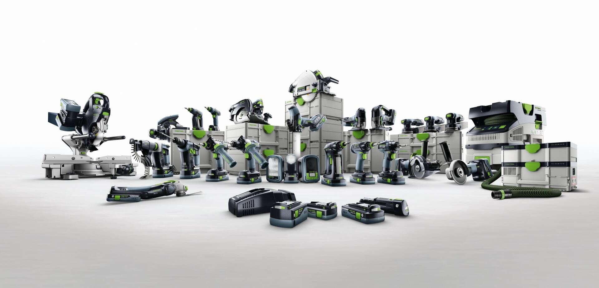 Auf weißem Hintergrund sind verschiedene Elektrowerkzeuge und Zubehörteile von Festool aufgereiht, darunter Sägen, Bohrmaschinen, Schleifer, Akkus und Aufbewahrungsboxen, die alle mit grauen, schwarzen und grünen Akzenten versehen sind.