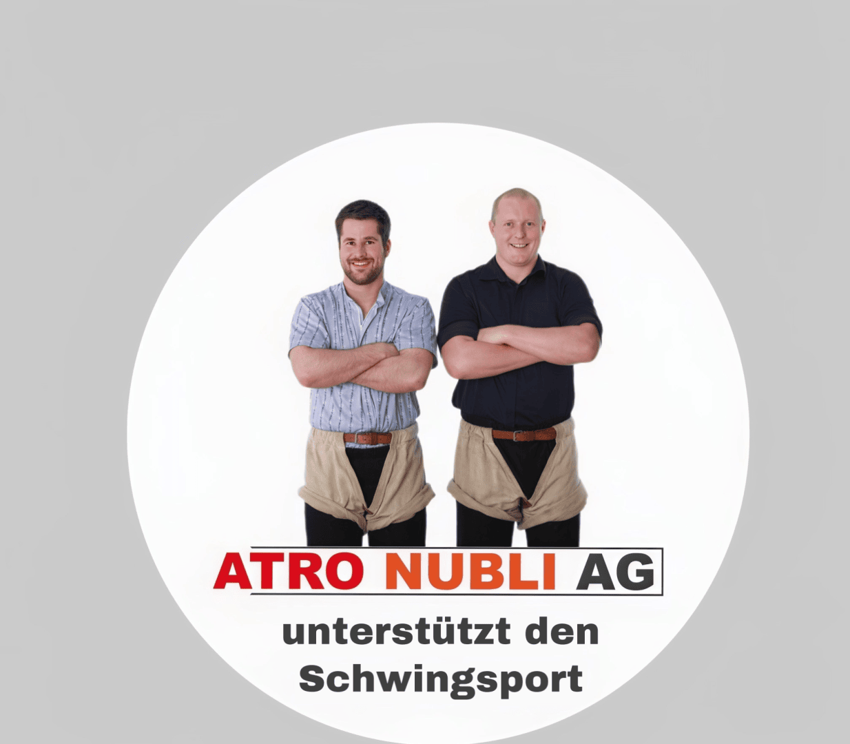 Zwei Männer stehen mit verschränkten Armen nebeneinander, in traditioneller Schweizer Ringerkleidung, vor einem weißen Hintergrund. Darunter steht der Text ATRO NUBLI AG unterstützt den Schwingsport.