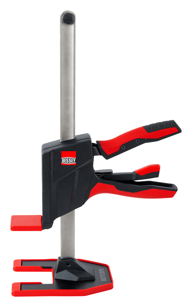 Une pince BESSEY rouge et noire avec des mâchoires rembourrées et des poignées ergonomiques, à la verticale avec une barre métallique solide et un pied large.