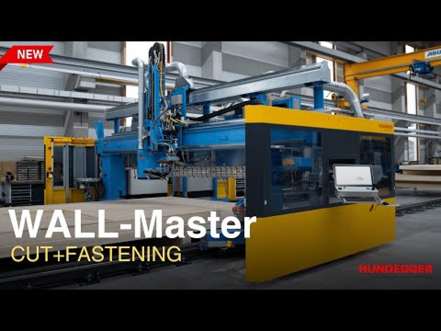 Eine große industrielle WALL-Master Schneide- und Befestigungsmaschine in einer Fabrikumgebung. Die Maschine ist blau und gelb, ein Kontrollbildschirm ist sichtbar. Der Text lautet: WALL-Master Cut + Fastening und Hundegger.