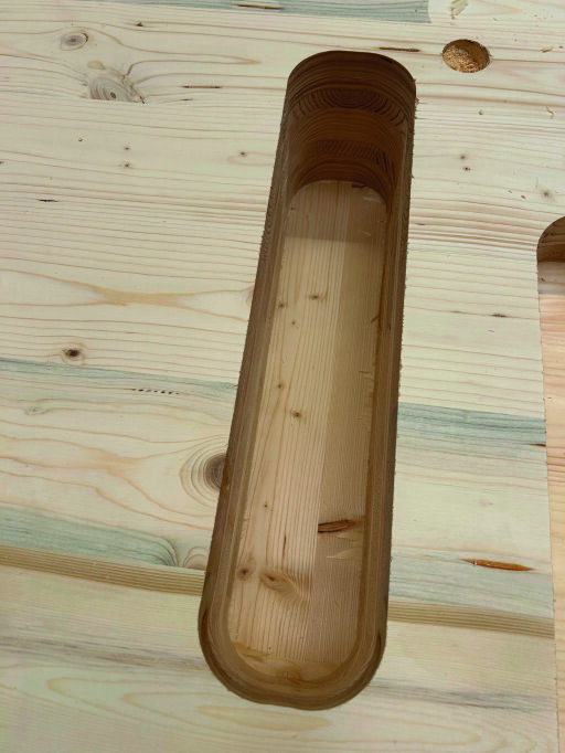 Eine Nahaufnahme einer rechteckigen Nut mit abgerundeten Kanten, die in ein helles Holzbrett geschnitten wurde, zeigt die geschichtete Maserung und die glatte Oberfläche des geschnitzten Teils.