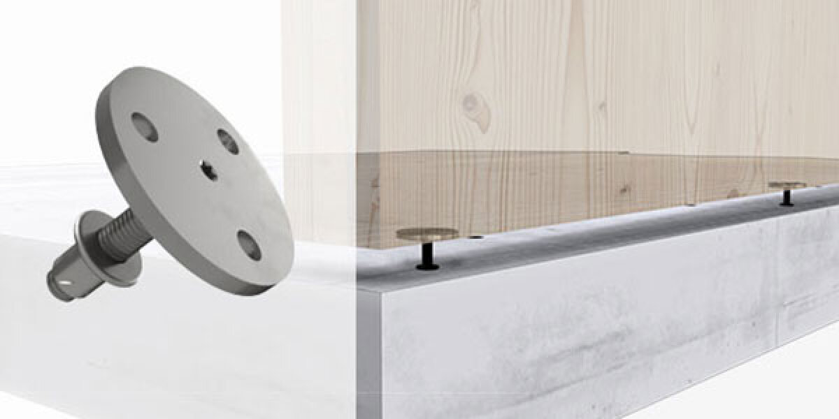 Eine Metallbefestigung mit einer runden Platte und einer Schraube wird im Detail gezeigt, um zu veranschaulichen, wie sie eine Holzplatte auf einem Betonsockel befestigt. Das Befestigungselement geht durch das Holz und wird im Beton verankert.