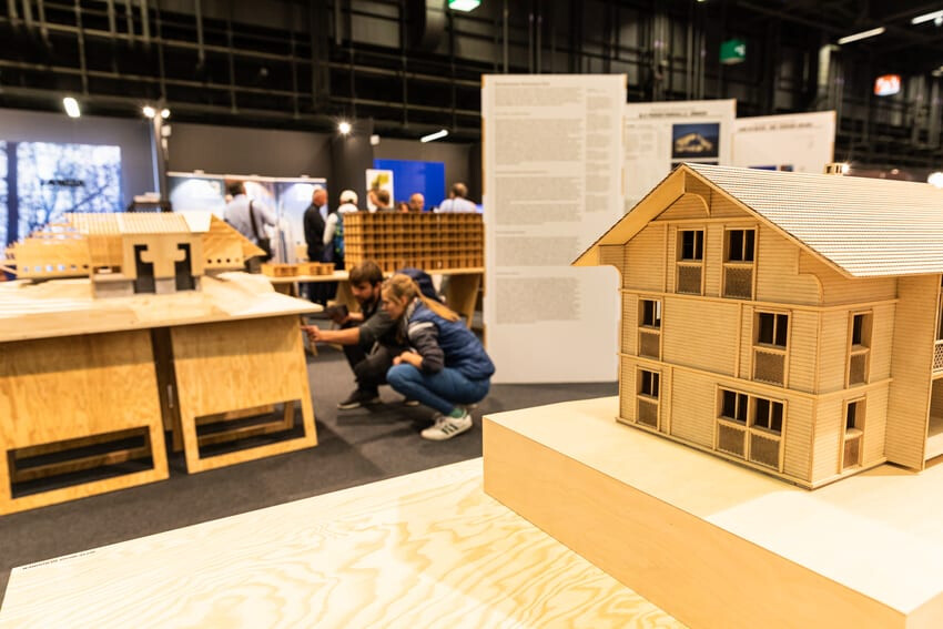 Visiteurs intéressés par des modèles de construction en bois.