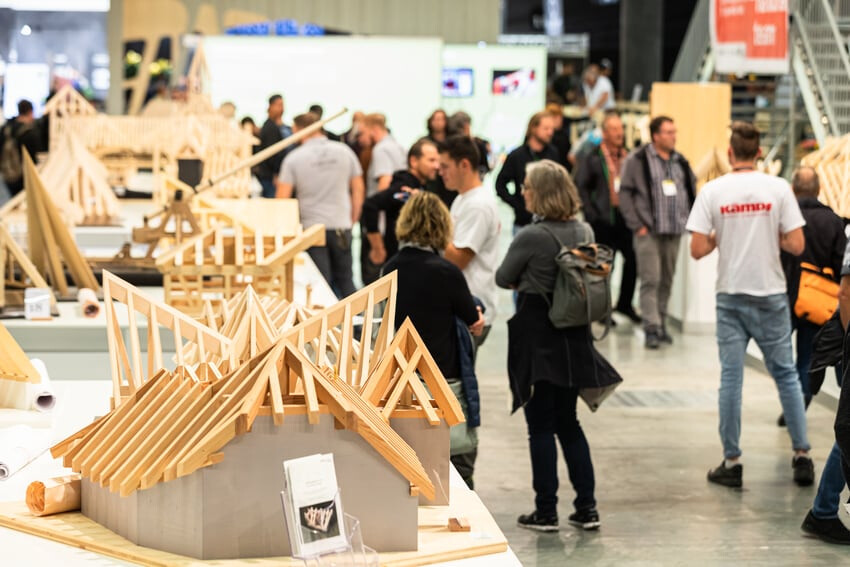 Visiteurs dans le hall d'exposition et modèle en bois au premier plan.